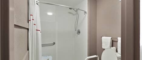 Un baño con ducha, inodoro y toallero.