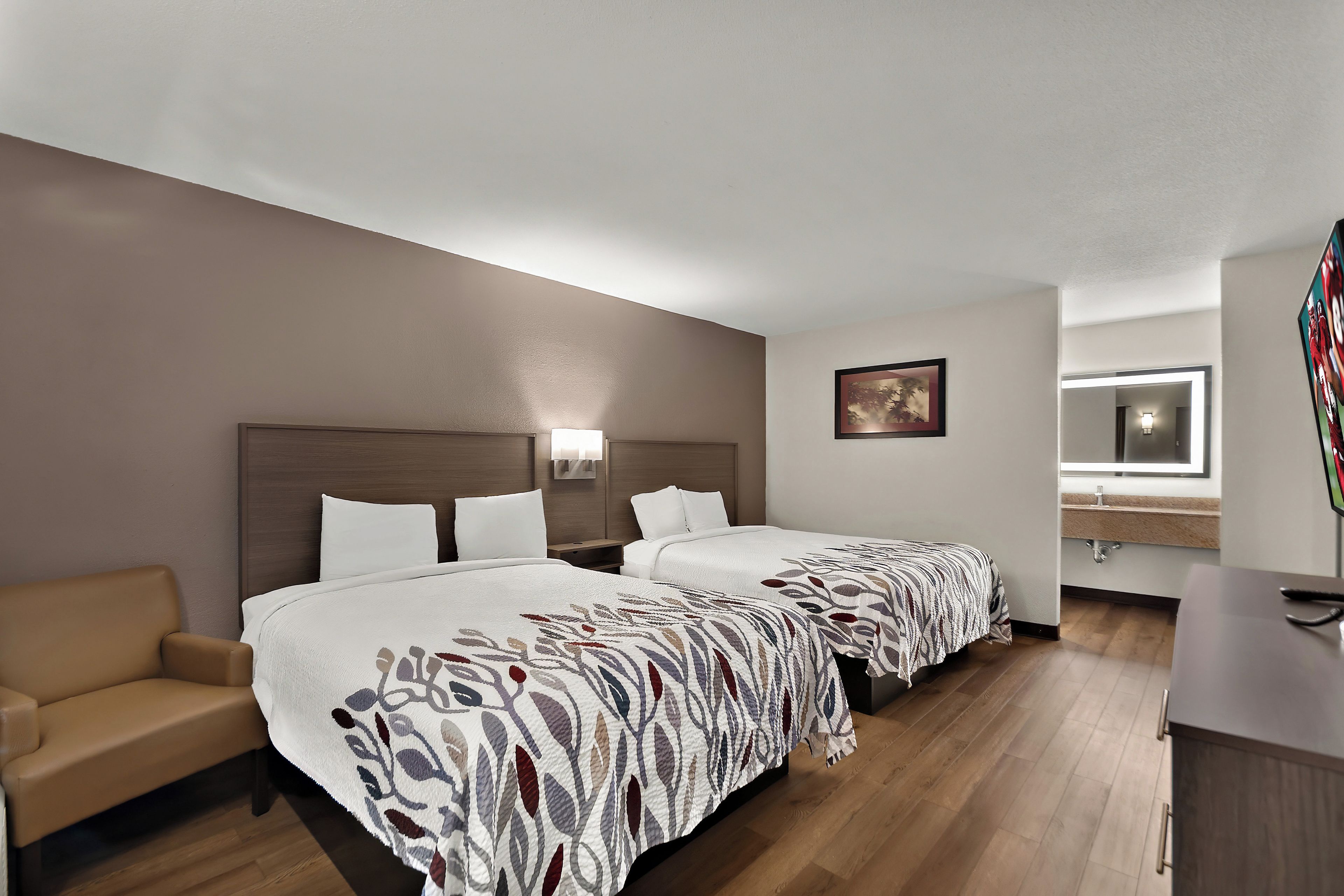 Une chambre d’hôtel avec deux lits, un canapé, un bureau et un miroir dans la salle de bain.
