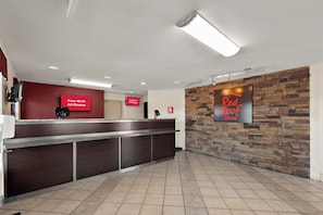 A hotel reception area with a modern design, including a reception desk, a stone accent wall, and a sign indicating free Wi-Fi availability. - Red Roof Inn Winchester, VA (Winchester)