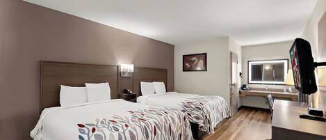 Une chambre d’hôtel avec deux lits, un bureau, une télévision et une fenêtre.