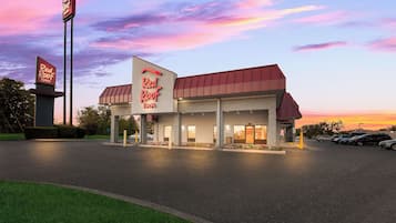 A Red Roof Inn with a large sign, a parking lot, and a sunset sky.