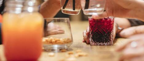 A group of people holding glasses with straws, a jar of orange liquid, and a glass with a red liquid.