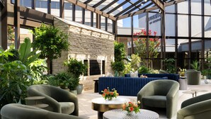 A spacious indoor patio with comfortable seating, a stone wall, and a glass ceiling. - DoubleTree by Hilton Fairfield Hotel & Suites (Fairfield)