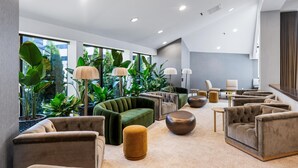 A modern lounge area with multiple seating options, including sofas and armchairs, arranged around a central coffee table. Large windows provide views of greenery outside. - DoubleTree by Hilton Fairfield Hotel & Suites (Fairfield)