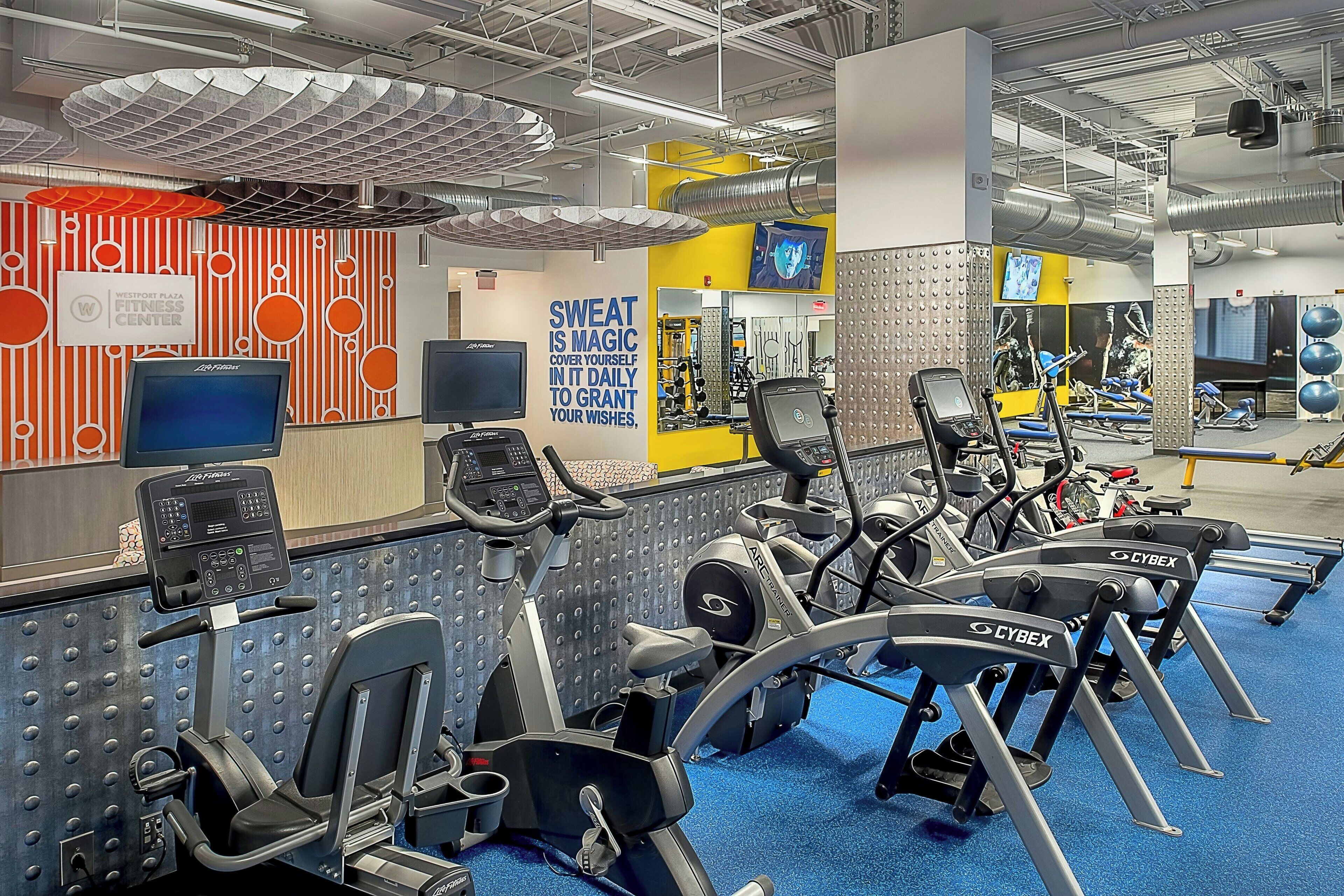 A gym with stationary bikes, a treadmill, and a wall with motivational text.