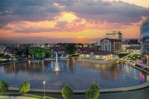 A lakeside view of a hotel with a fountain, surrounded by trees and modern buildings. - Sheraton Westport Chalet Hotel St. Louis (Maryland Heights)