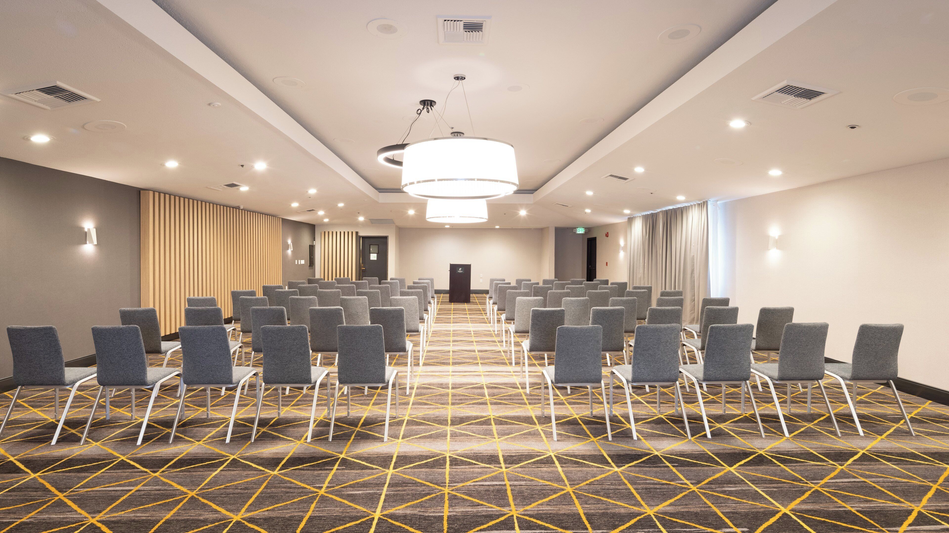 A conference room with rows of chairs, a patterned carpet, and a large chandelier.
