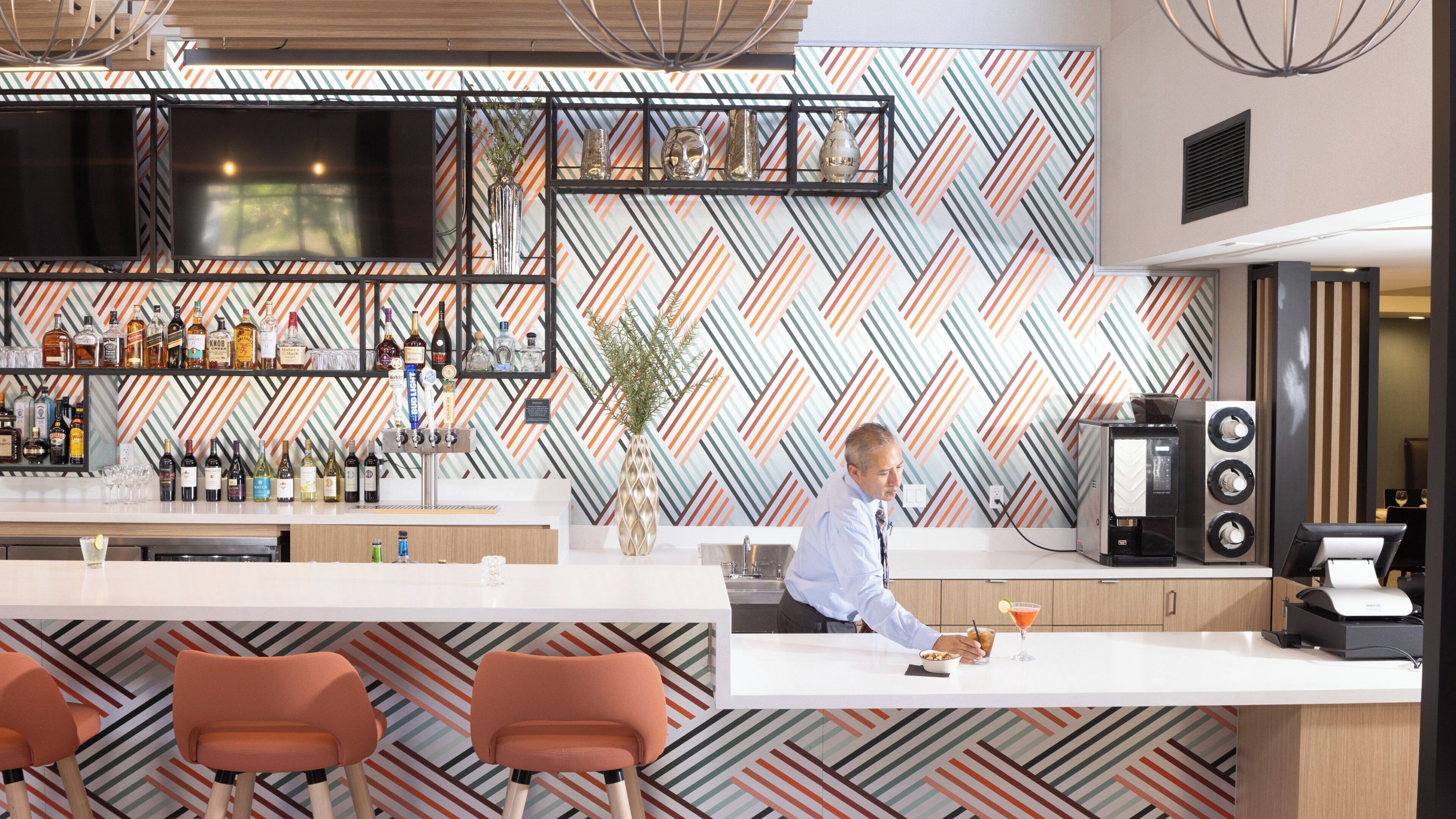Zona de bar con pared estampada, televisor de pantalla plana y cafetera.