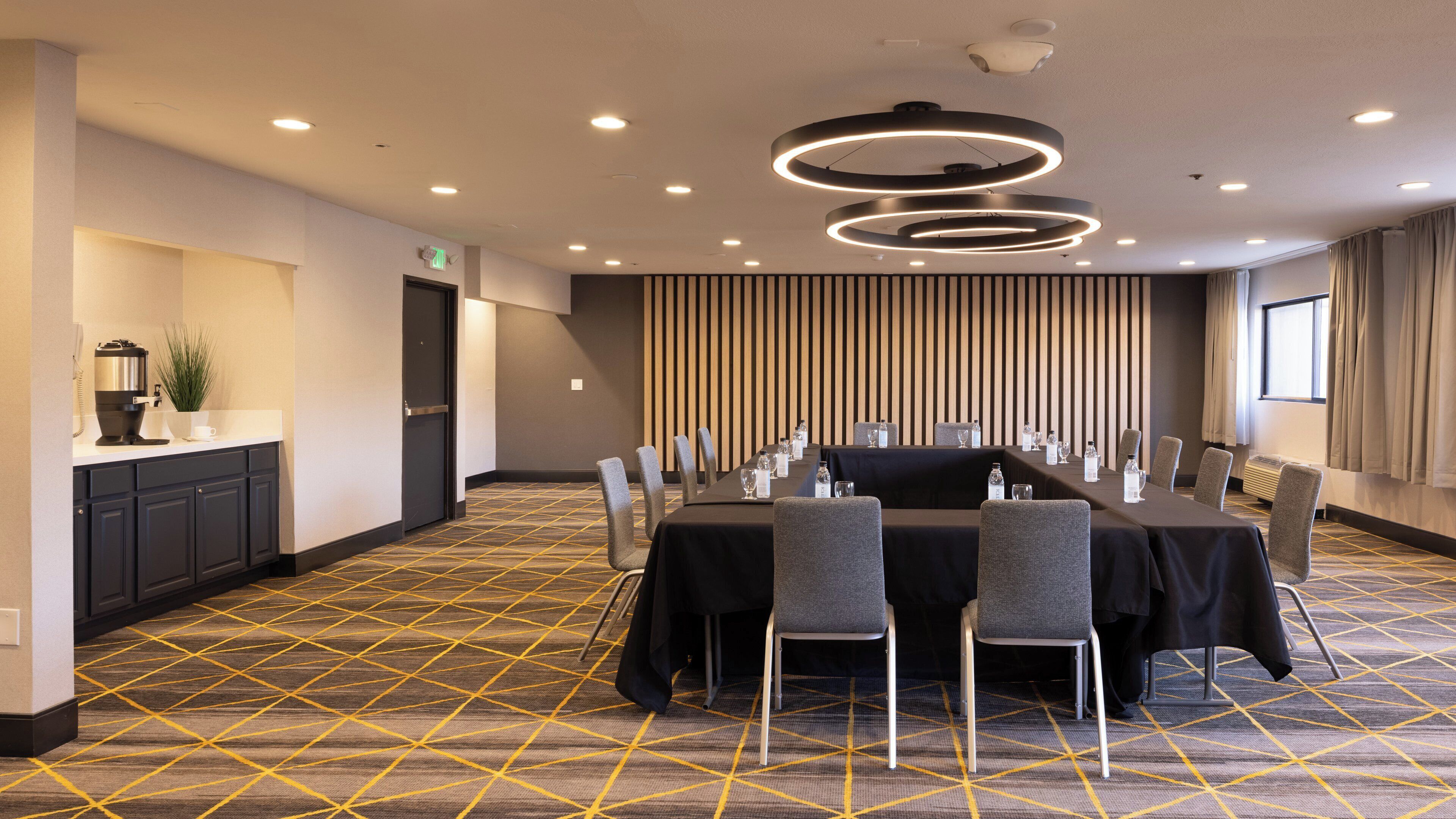 A conference room with a long table, chairs, and a patterned carpet.