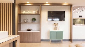 A modern kitchen with a built-in TV, wooden shelves, and a green cabinet.