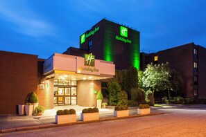 Un hôtel Holiday Inn doté d'un espace de réception, d'une grande enseigne lumineuse et d'une entrée bien éclairée.