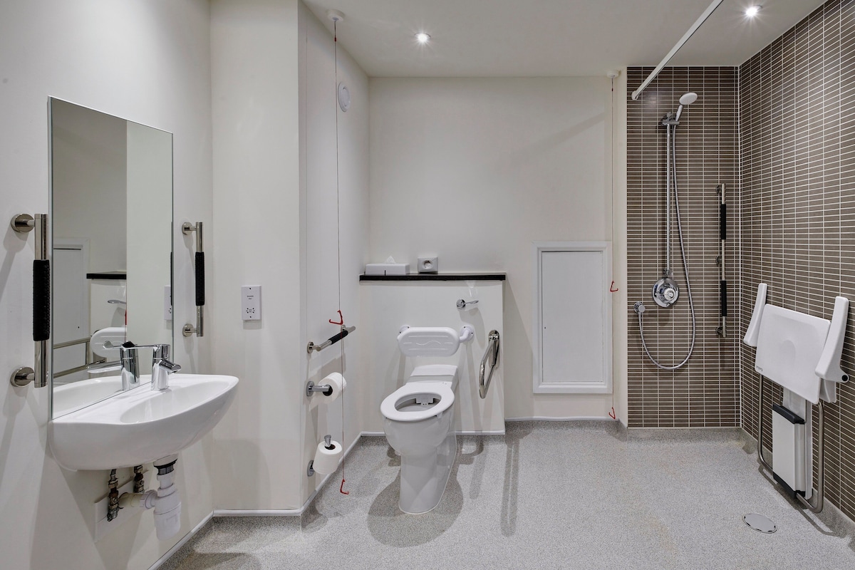 A modern bathroom with a white sink, toilet, and shower.