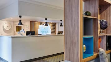 A hotel reception area with a reception desk, a clock, and a sign indicating 'Holiday Inn'.