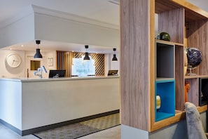 A hotel reception area with a reception desk, a clock, and a sign indicating 'Holiday Inn'. - Holiday Inn Haydock M6 Jct23 by IHG (Newton-le-Willows)