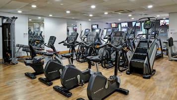 Un gimnasio con varias máquinas de cardio, incluyendo cintas de correr y elípticas, dispuestas en filas.