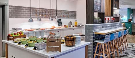 Un mostrador de desayuno con diferentes alimentos y una zona de estar con sillas.