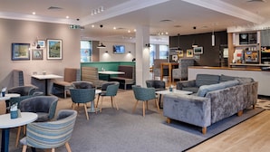 A modern lounge area with seating arrangements, a bar area, and a television screen.