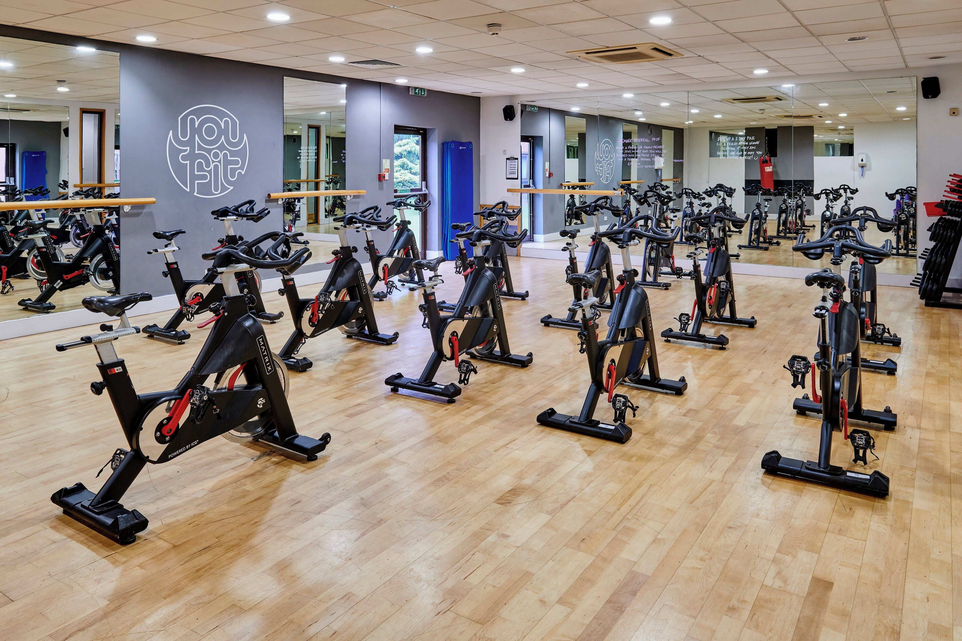 Un gimnasio con varias bicicletas estáticas dispuestas en filas.