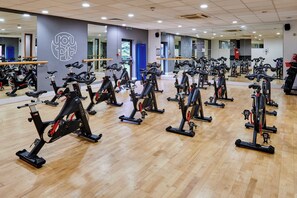 Een sportschool met meerdere vastgezet fietsen, gerangschikt in rijen.