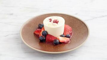 A dessert on a plate with strawberries and blueberries.