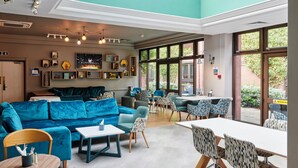 A modern interior with a blue sofa, dining area, and large windows.
