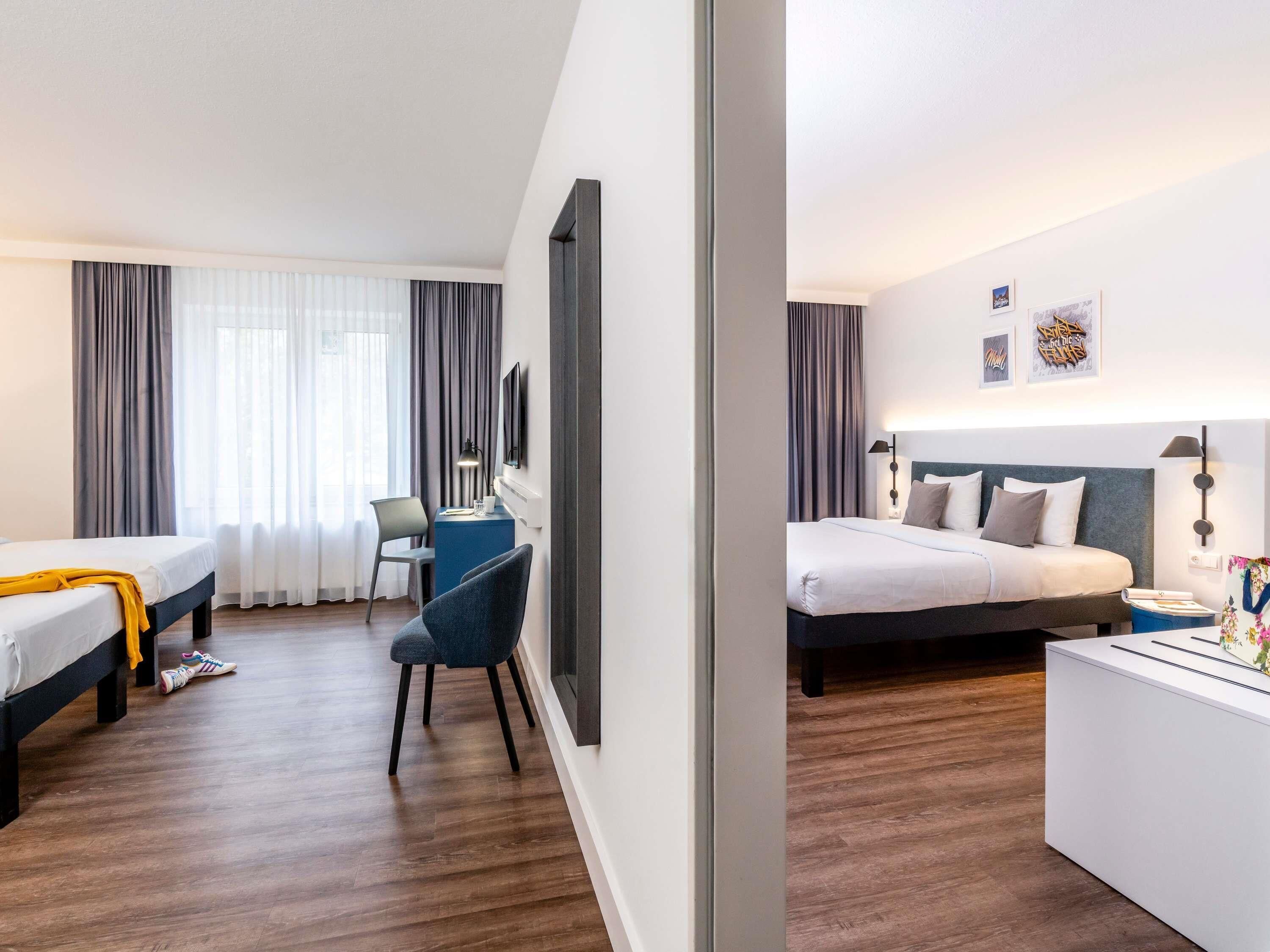 A hotel room with two beds, a desk, and a chair.