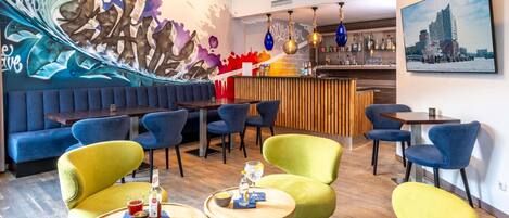 Eine moderne Bar mit Wandgemälde, Sitzgelegenheiten und Blick auf die Stadt.