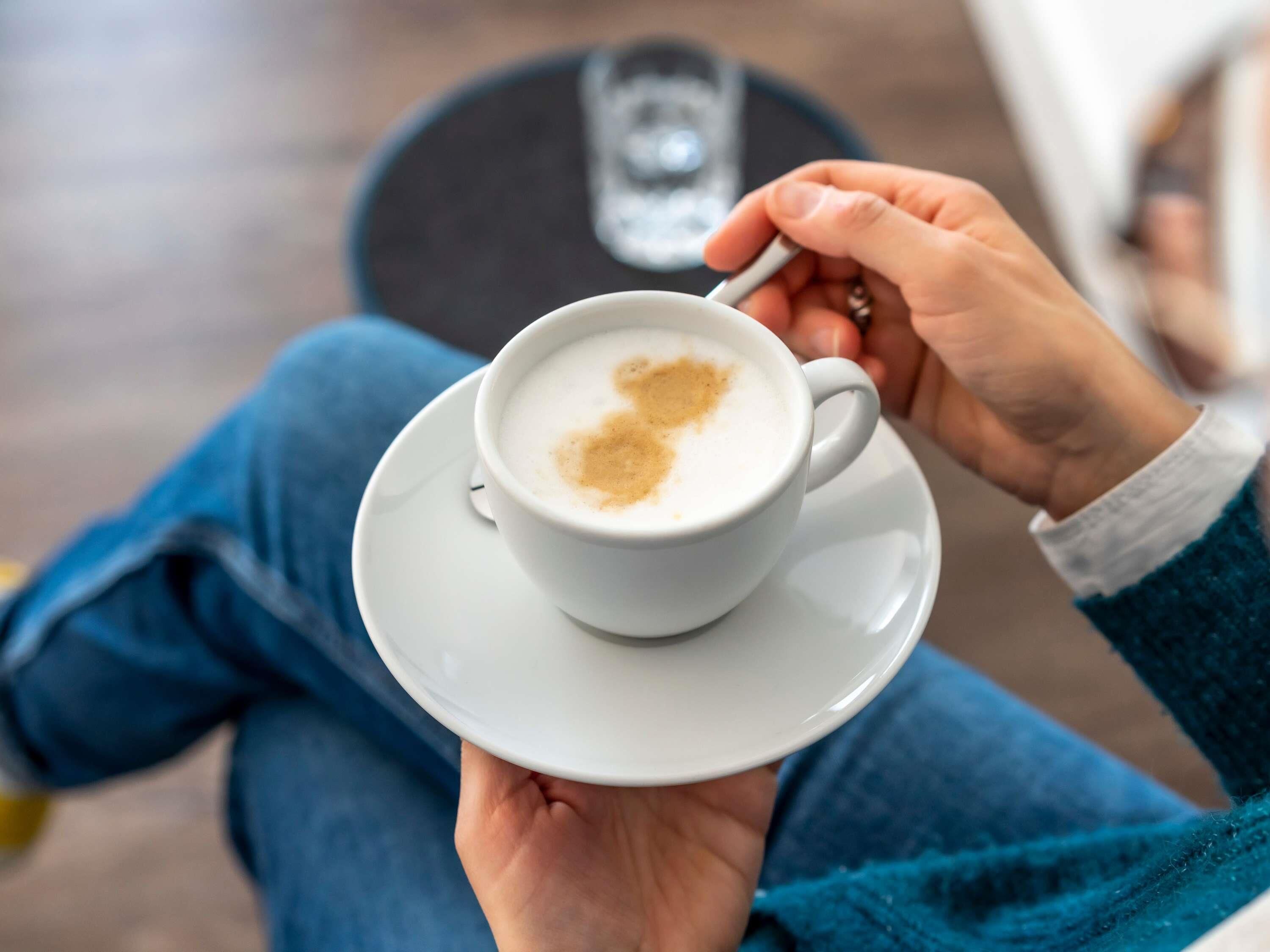 En person sidder i en stol med en kop kaffe og en ske.