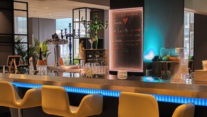 Zona de bar con mostrador iluminado con neón, taburetes y un menú en pizarra.