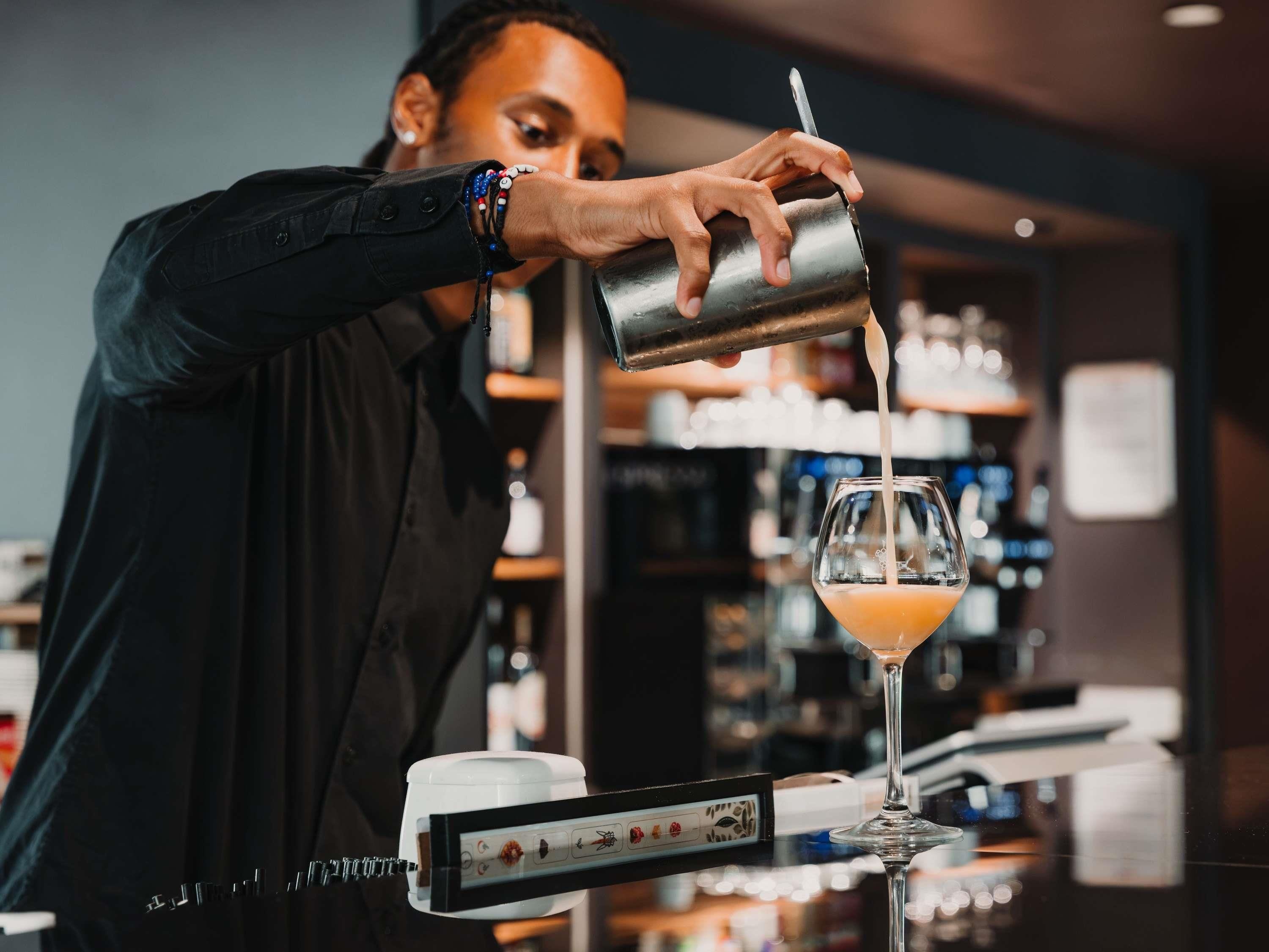 Ein Barkeeper gießt ein Getränk ein.