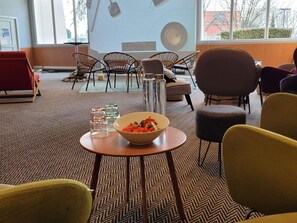 Een vergaderruimte met een groot scherm, meerdere stoelen, een tafel met een schaal lekkernijen en een kamerbreed tapijt.