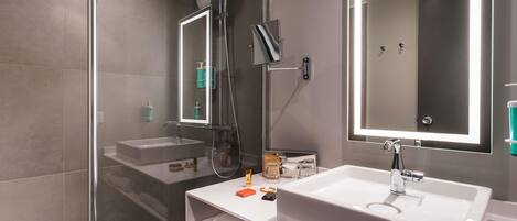 A modern bathroom with a glass-enclosed shower, a large mirror, and a white sink.