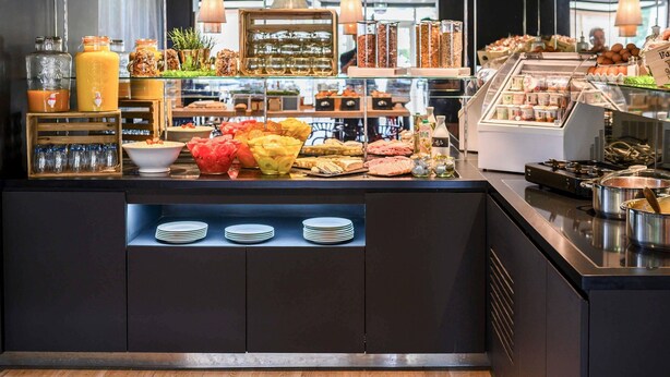 Un bufé de desayuno con diferentes opciones de comida, frascos de vidrio y una máquina de café.