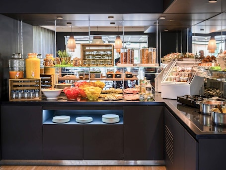 A breakfast buffet with various food items, glass jars, and a coffee machine.. Novotel Evry Courcouronnes
