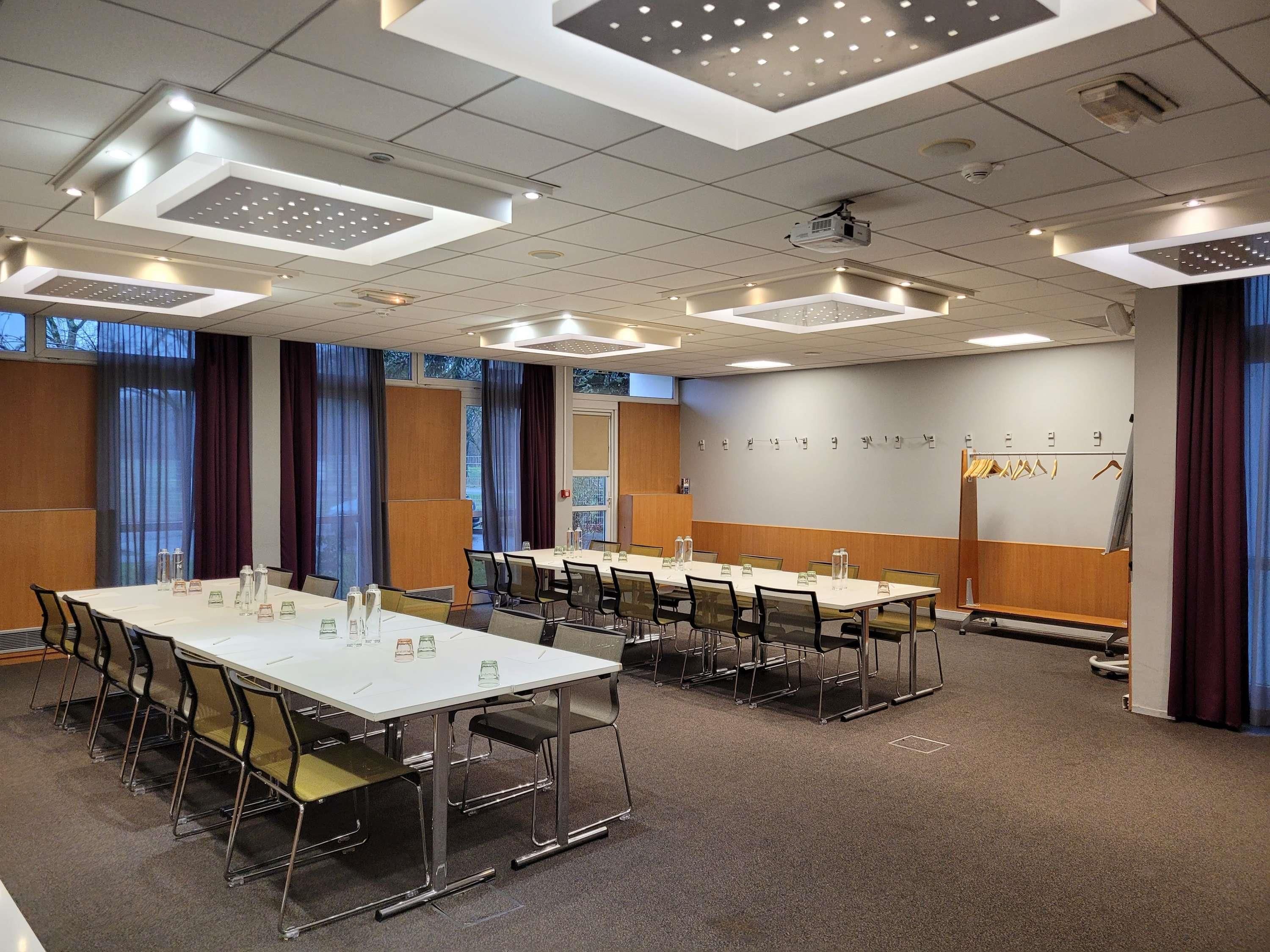 A conference room with a long table, chairs, a projector, and a whiteboard.