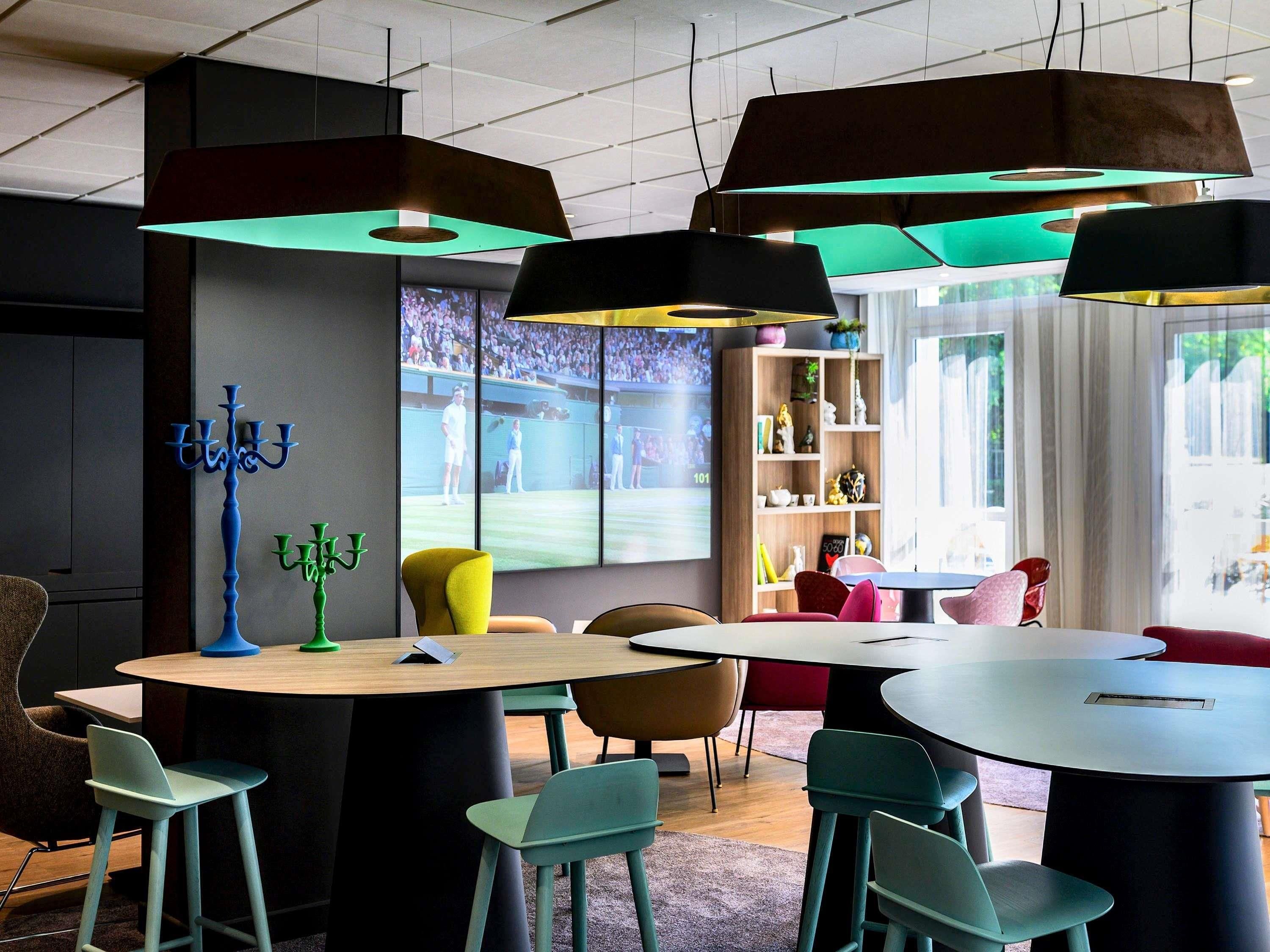Un interior moderno con mesas redondas, sillas coloridas e iluminación colgante.