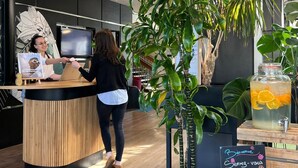 Un mostrador de recepción con una pantalla digital, una encimera de madera y un letrero que dice 'Bienvenue' y 'Welcome'.