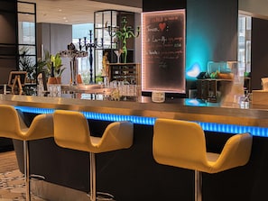 Zona de bar con mostrador iluminado con neón, taburetes y un menú en pizarra.