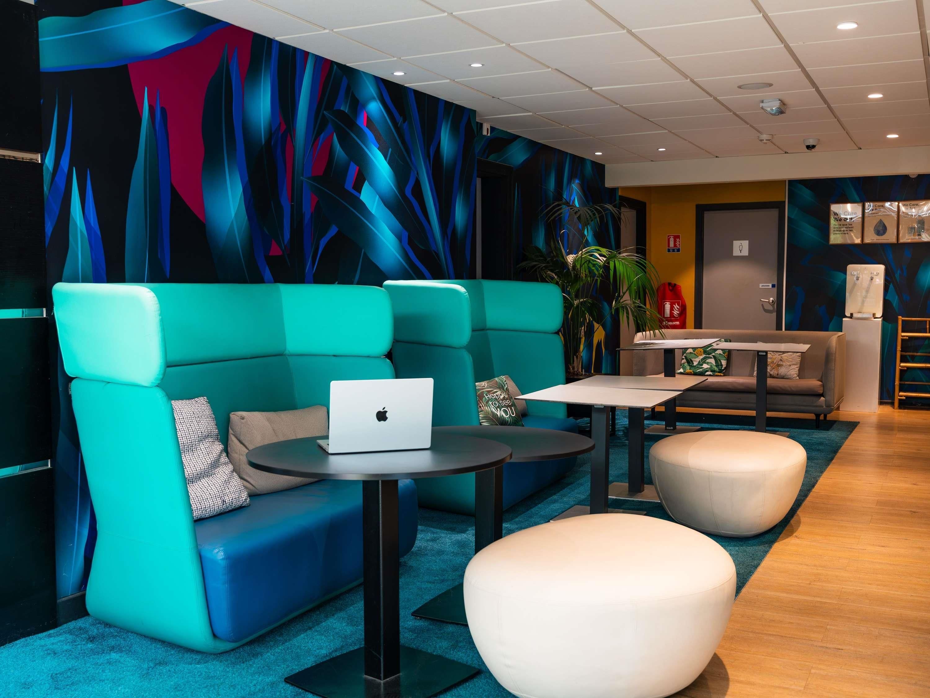 A modern lounge area with teal seating, a laptop on a table, and a water dispenser.