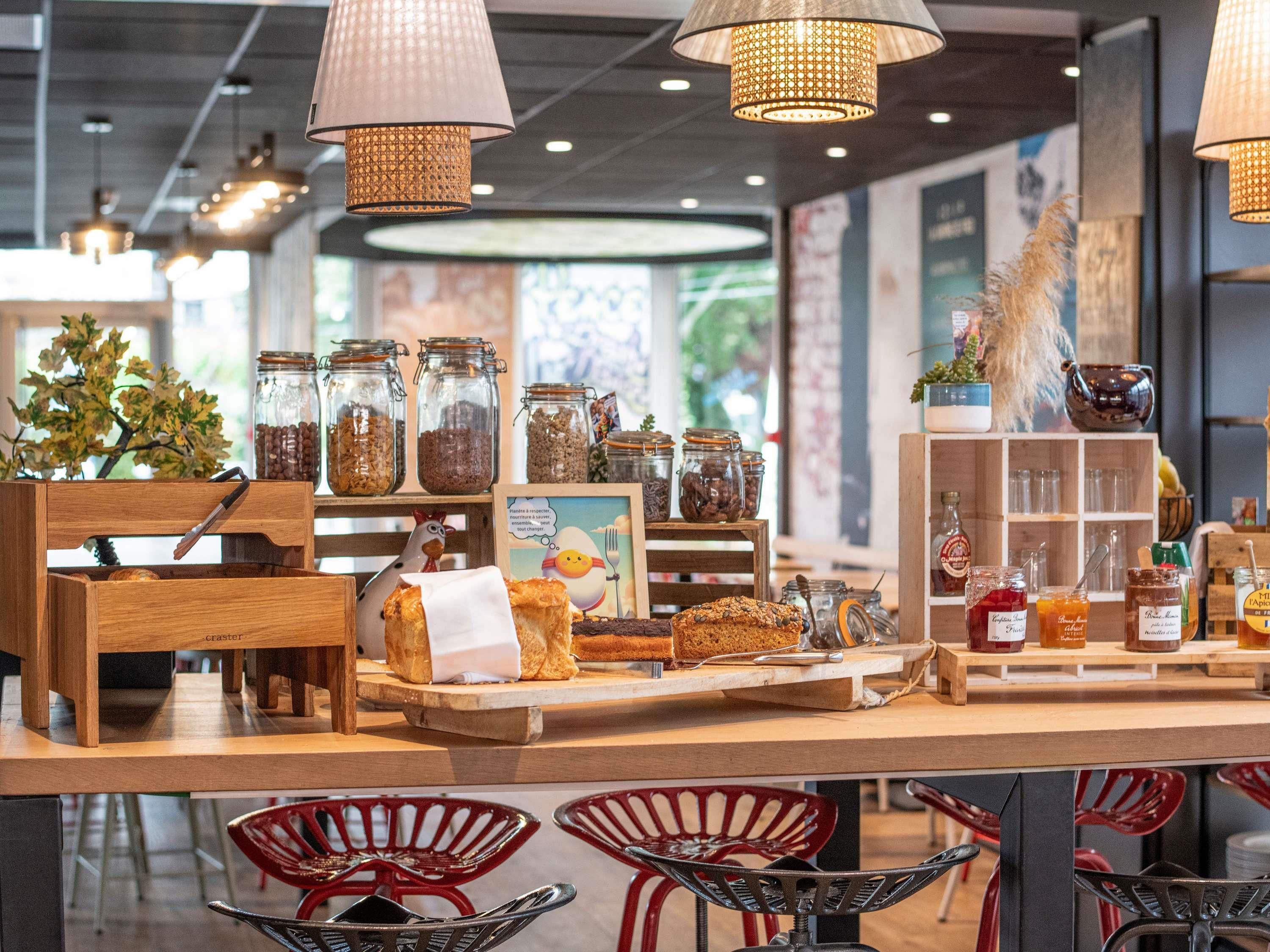A café interior with wooden furniture, hanging lamps, and jars of food items.