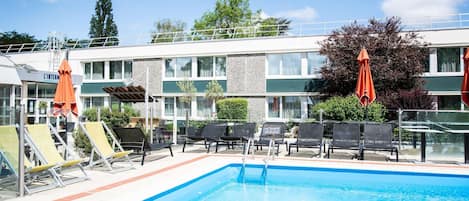 Una piscina al aire libre de temporada, sillones reclinables de piscina