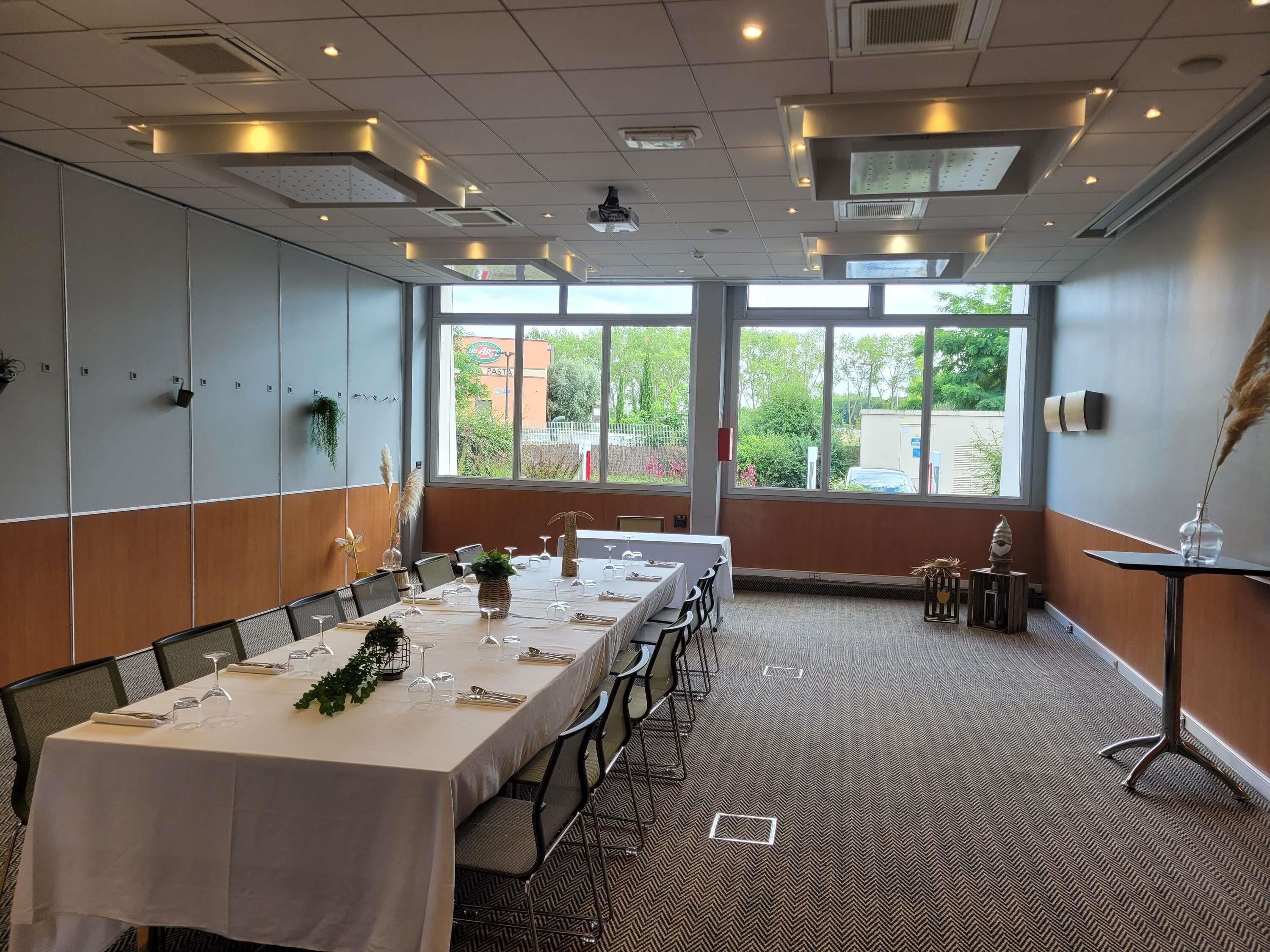 A conference room with a long table, chairs, and large windows.