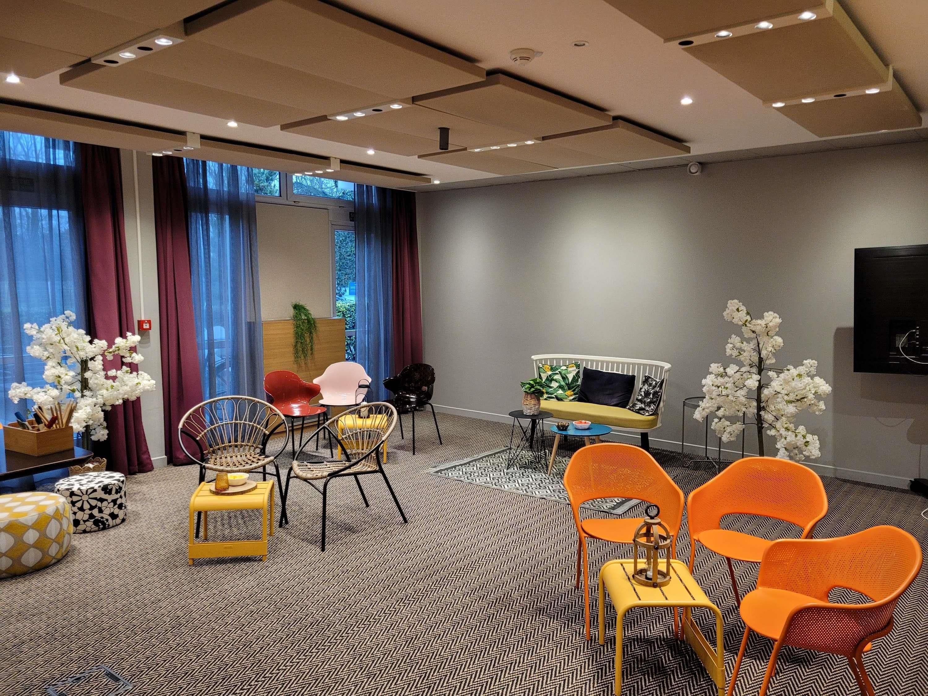 Ein modernes Hotelzimmer mit einer Couch, Sesseln, einem kleinen Tisch und einem Fernseher an der Wand.