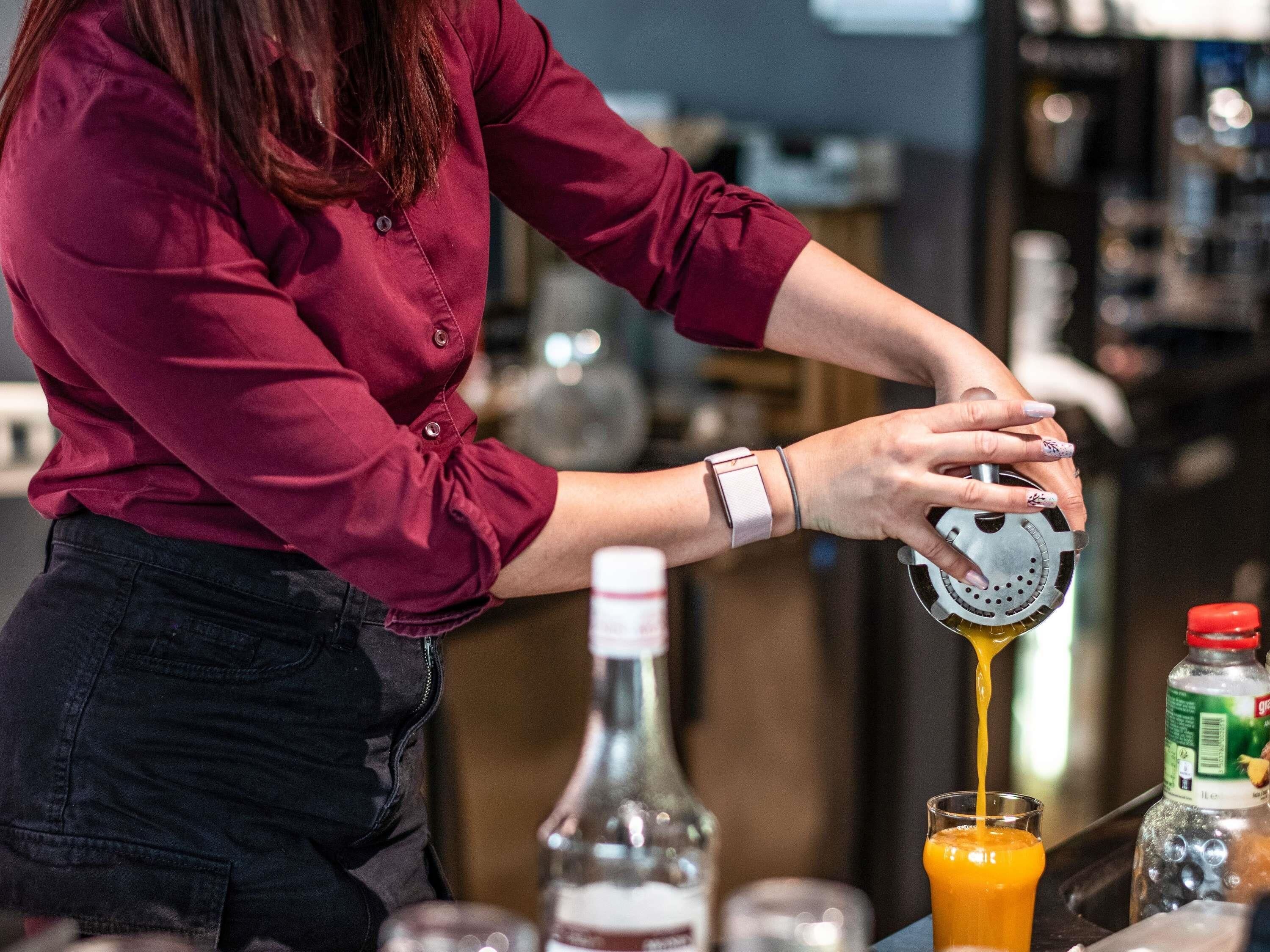 A person pouring a yellow liquid into a glass.