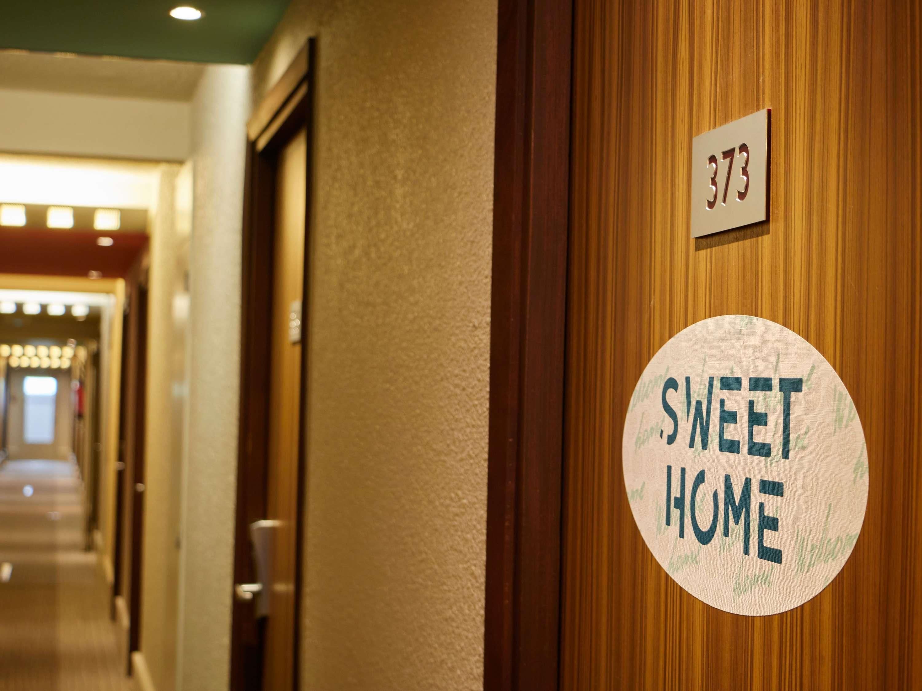 Un couloir avec une porte portant le numéro « 373 » et une pancarte sur laquelle on peut lire « SWEET HOME ».
