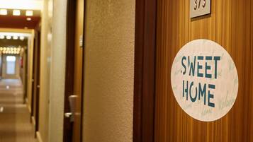 Un couloir avec une porte portant le numéro « 373 » et une pancarte sur laquelle on peut lire « SWEET HOME ».