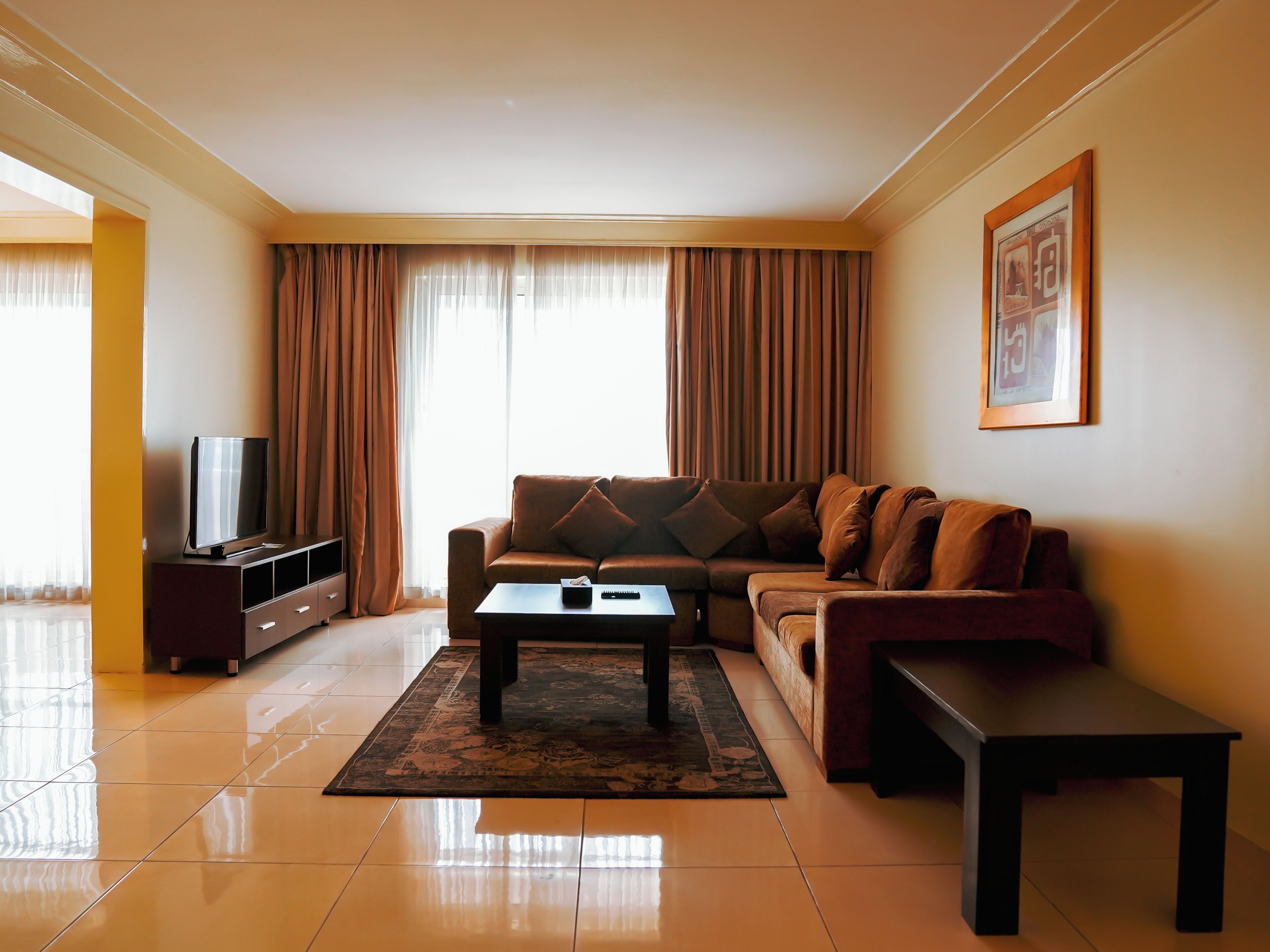 A living room with a sofa, a coffee table, a TV on a stand, and a framed picture on the wall.