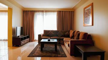 A living room with a sofa, a coffee table, a TV on a stand, and a framed picture on the wall.