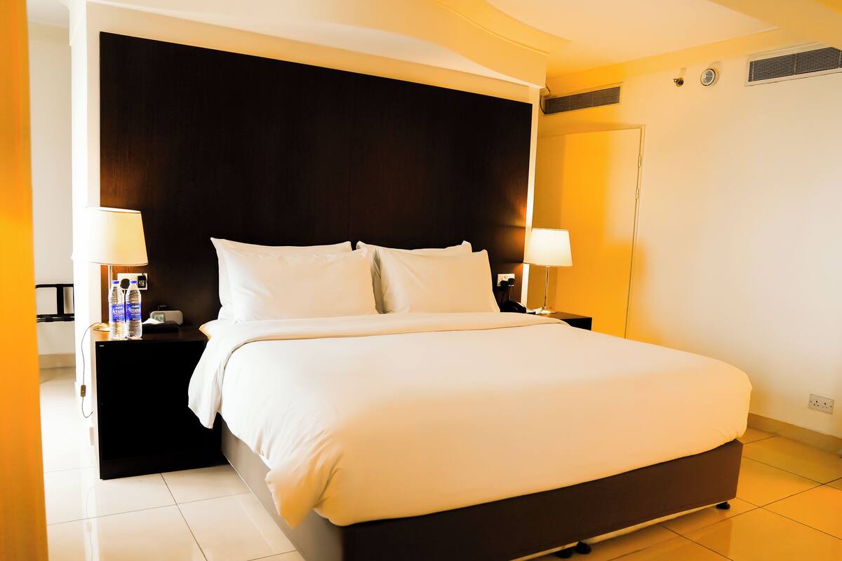 A neatly made bed with white linens in a hotel room.