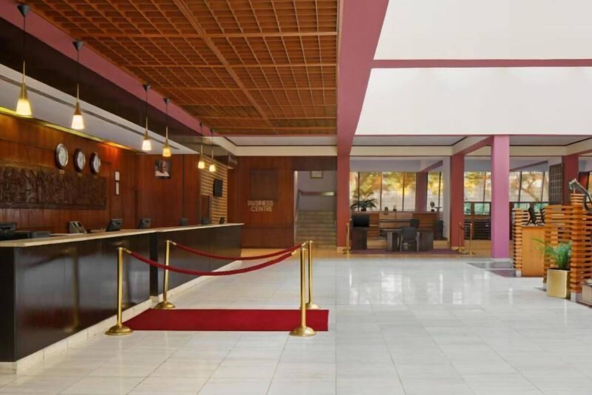 A reception area with a wooden reception desk, a red carpet, and a staircase leading to a seating area.